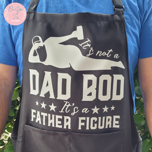 Black Apron With White Design of It's not a Dad Bod Its a Father Figure BY Once Upon A Celeb Design